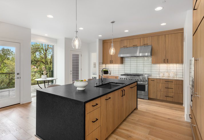 Beautiful kitchen in new luxury home with waterfall quartz island, pendant lights and hardwood floors.
